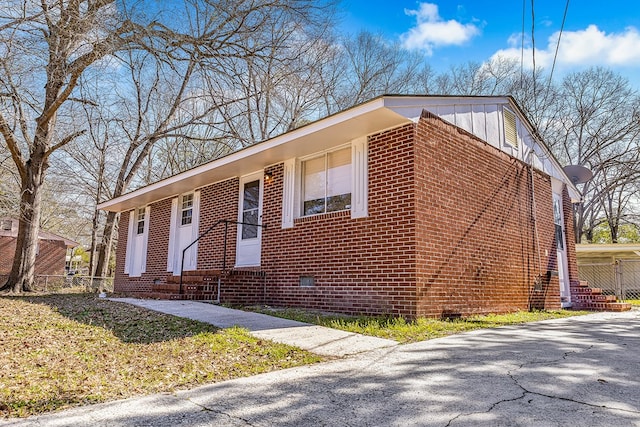 view of front of home with board and batten siding, entry steps, crawl space, and brick siding