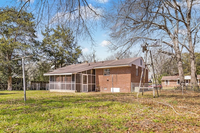 back of house with a sunroom, brick siding, a lawn, and fence