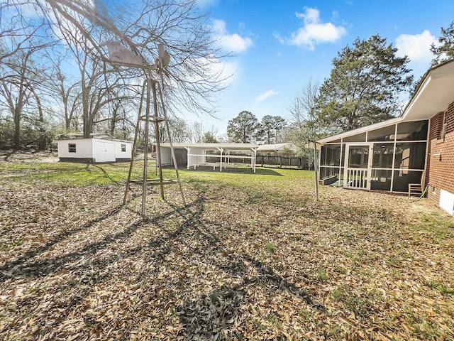 view of yard with an outbuilding, a sunroom, fence, and a storage shed