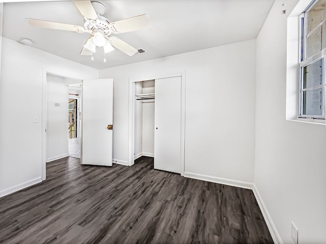 unfurnished bedroom featuring ceiling fan, a closet, baseboards, and dark wood-type flooring