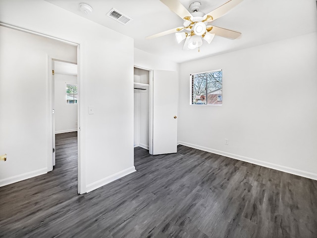 unfurnished bedroom featuring dark wood-style floors, visible vents, baseboards, and multiple windows