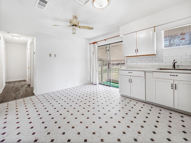 kitchen featuring baseboards, visible vents, a sink, white cabinetry, and backsplash