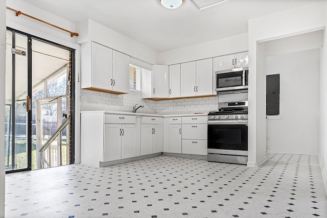 kitchen featuring light countertops, backsplash, appliances with stainless steel finishes, white cabinets, and electric panel