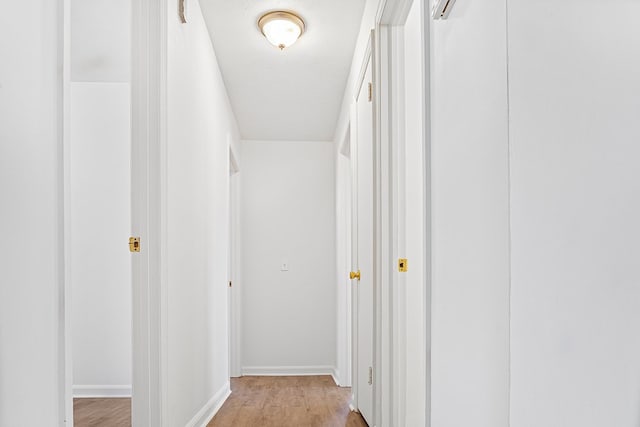 hall featuring baseboards and light wood finished floors