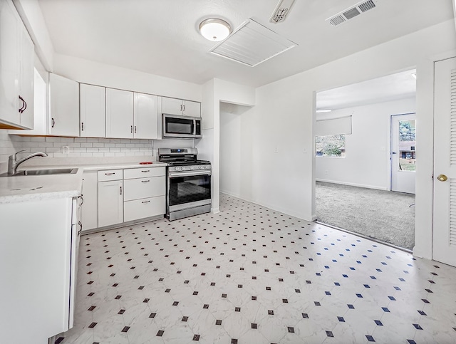 kitchen with a sink, visible vents, light countertops, appliances with stainless steel finishes, and light floors