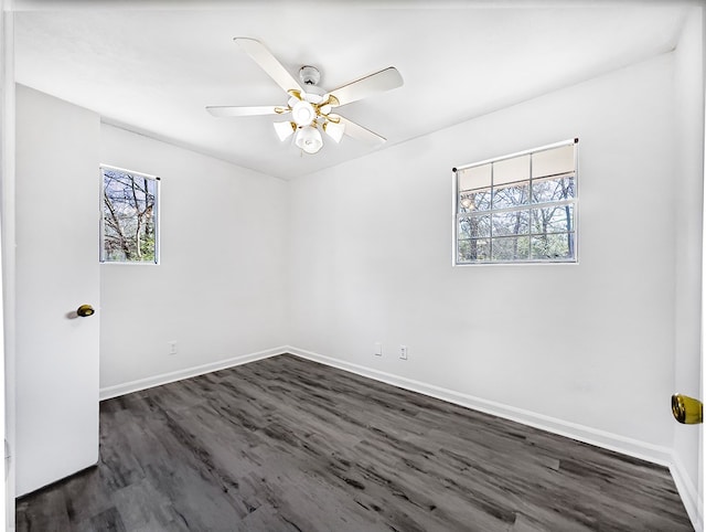 unfurnished room with dark wood-type flooring, a ceiling fan, and baseboards