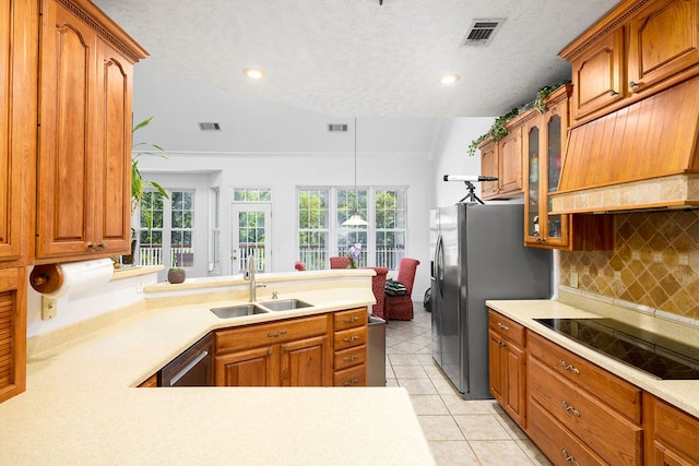 kitchen with sink, a textured ceiling, vaulted ceiling, light tile patterned flooring, and appliances with stainless steel finishes