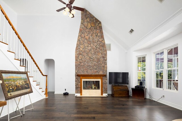 unfurnished living room featuring ceiling fan, a stone fireplace, dark wood-type flooring, and high vaulted ceiling