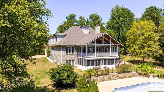 rear view of property with a sunroom and a balcony