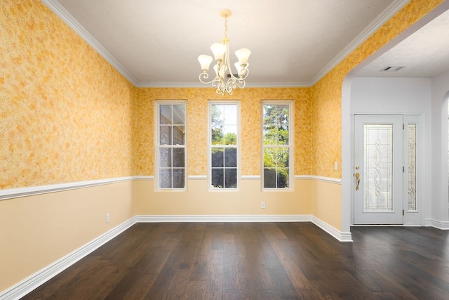 unfurnished dining area featuring crown molding, dark hardwood / wood-style floors, and an inviting chandelier