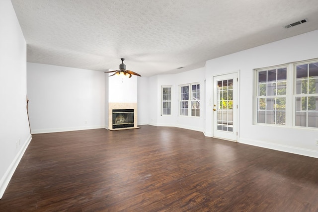 unfurnished living room featuring dark hardwood / wood-style floors, ceiling fan, and a textured ceiling