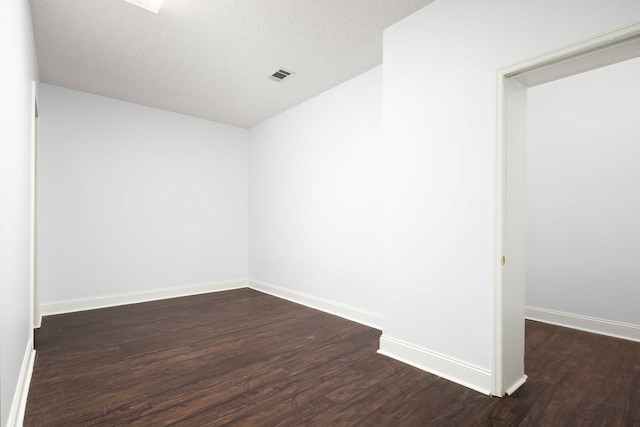 unfurnished room with a textured ceiling and dark hardwood / wood-style floors