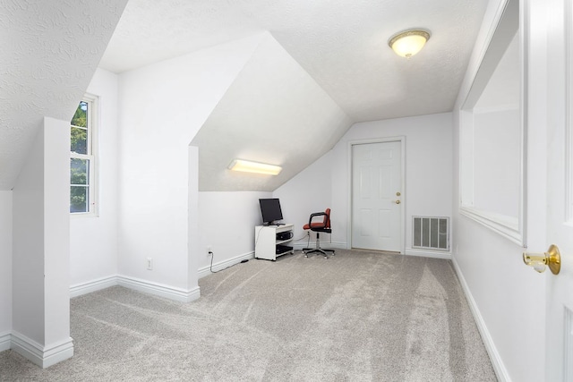 office area featuring a textured ceiling, light colored carpet, and lofted ceiling