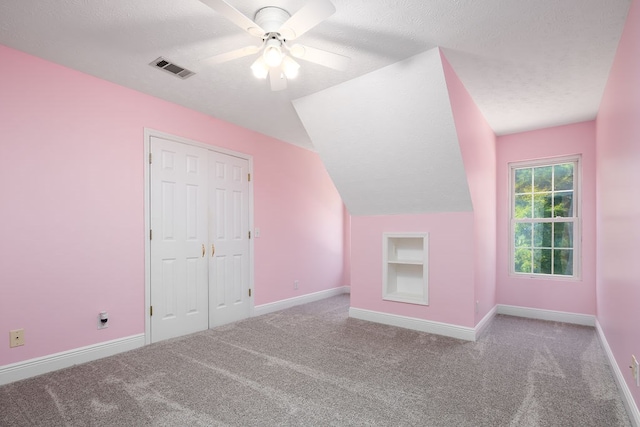 bonus room featuring a textured ceiling, light colored carpet, vaulted ceiling, and ceiling fan