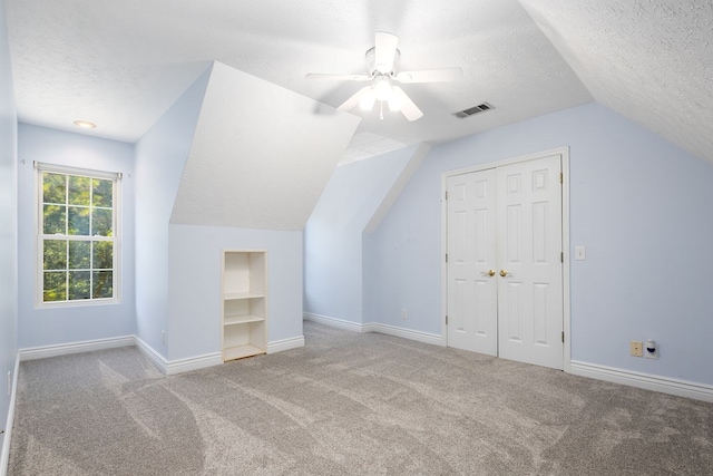 bonus room featuring lofted ceiling, light carpet, ceiling fan, and a textured ceiling