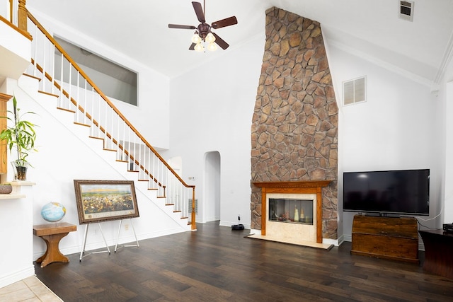 unfurnished living room featuring hardwood / wood-style floors, ceiling fan, a stone fireplace, and high vaulted ceiling