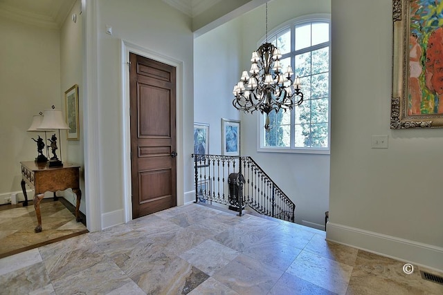 foyer entrance with crown molding and an inviting chandelier