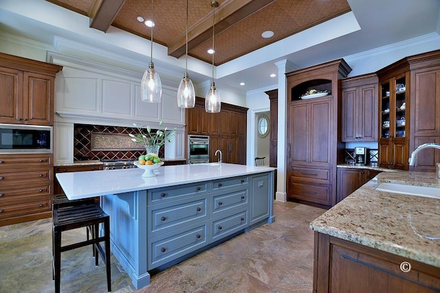 kitchen featuring stainless steel microwave, sink, hanging light fixtures, beamed ceiling, and a spacious island