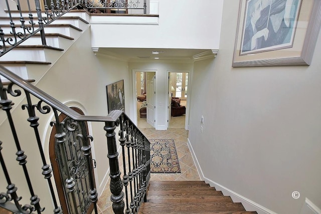 staircase with crown molding and tile patterned flooring