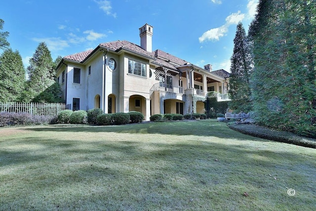 back of house featuring a yard and a balcony