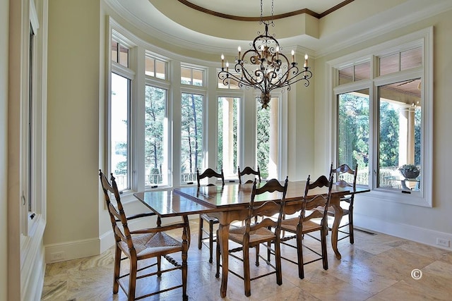 dining space featuring a raised ceiling, ornamental molding, and a chandelier