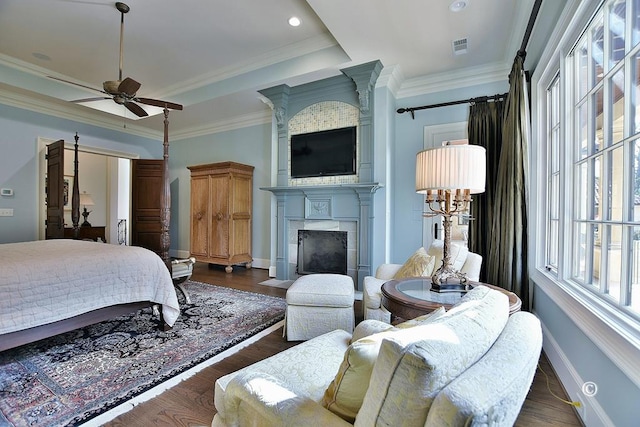 bedroom featuring a fireplace, dark wood-type flooring, ceiling fan, and ornamental molding