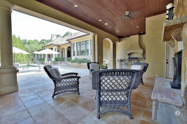 view of patio / terrace featuring an outdoor stone fireplace and ceiling fan