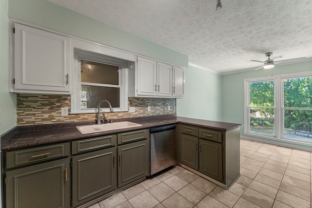 1506 Lokey Dr, Columbus, GA 31904 - kitchen with stainless steel dishwasher, a sink, dark countertops, a peninsula, and white cabinets