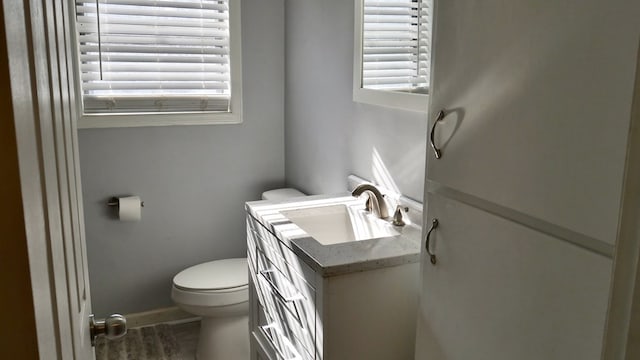 bathroom featuring a healthy amount of sunlight, vanity, and toilet