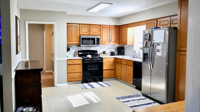 kitchen with sink, light tile patterned floors, backsplash, and black appliances