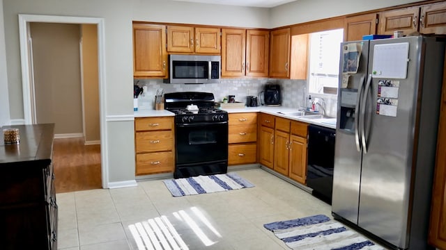 kitchen featuring sink, light tile patterned floors, decorative backsplash, and black appliances