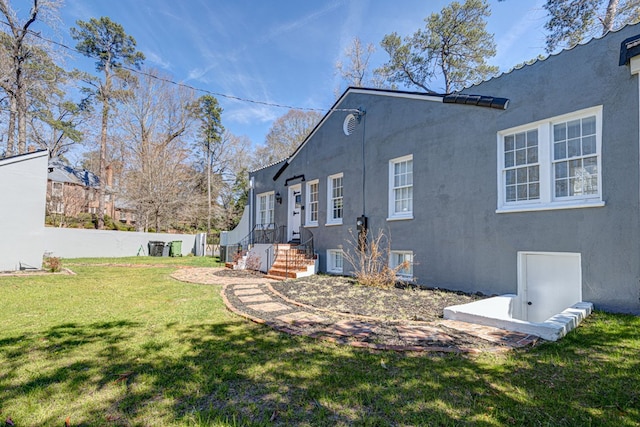 view of side of home featuring a lawn, fence, and stucco siding