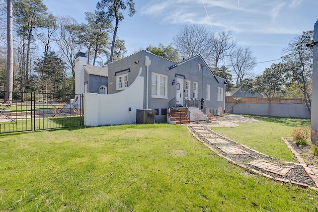 exterior space with a chimney, fence, a yard, central AC, and stucco siding