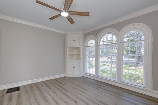 empty room with a healthy amount of sunlight, light wood-style flooring, visible vents, and crown molding