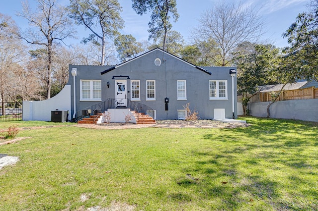 back of property with a lawn, fence, and stucco siding