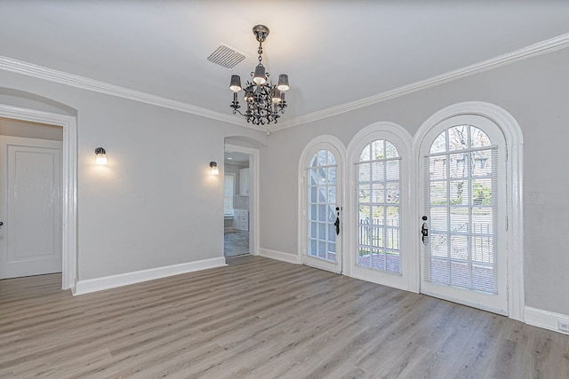 unfurnished room featuring arched walkways, crown molding, light wood finished floors, visible vents, and baseboards