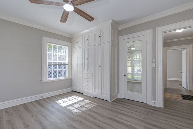 unfurnished bedroom with baseboards, light wood finished floors, visible vents, and crown molding