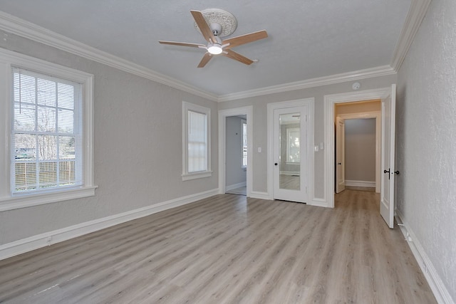 empty room featuring baseboards, a textured wall, light wood-style floors, and crown molding