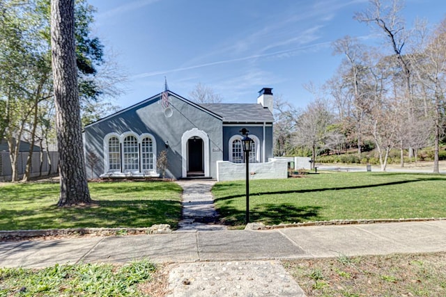 view of front of property featuring a front lawn, a chimney, and stucco siding