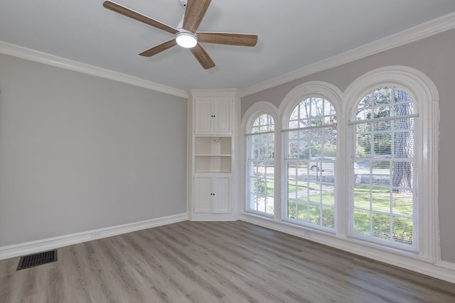 unfurnished room with baseboards, visible vents, crown molding, and light wood finished floors