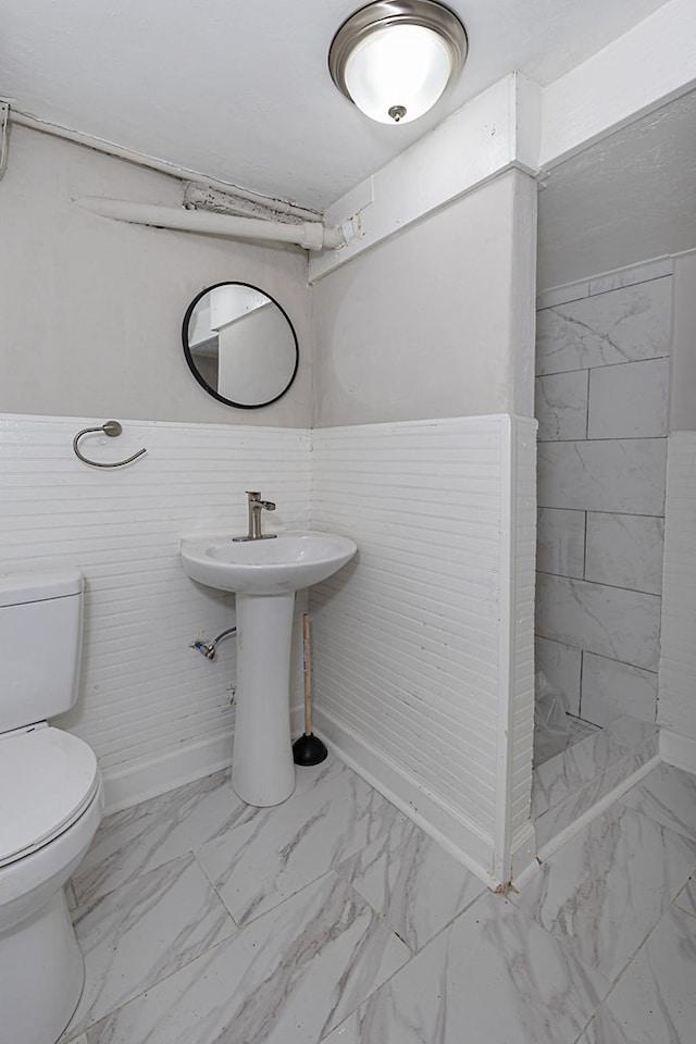 full bathroom with marble finish floor, toilet, a sink, tiled shower, and baseboards