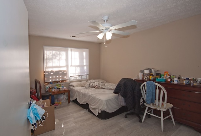 bedroom featuring ceiling fan, light hardwood / wood-style floors, and a textured ceiling