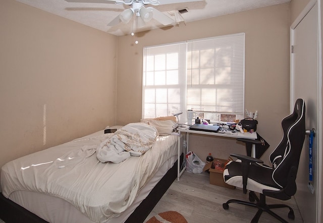 bedroom with ceiling fan, a textured ceiling, and light hardwood / wood-style flooring