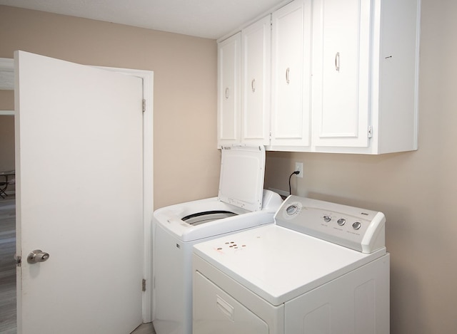 clothes washing area with cabinets and washer and clothes dryer