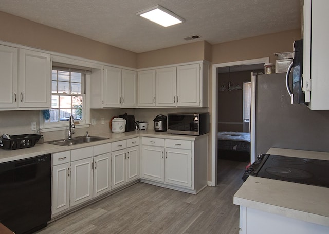 kitchen with light hardwood / wood-style floors, sink, white cabinetry, appliances with stainless steel finishes, and a textured ceiling