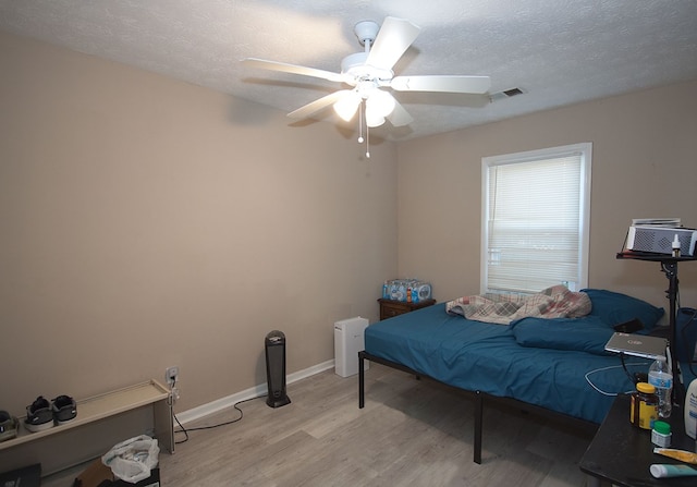 bedroom featuring ceiling fan, light hardwood / wood-style floors, and a textured ceiling