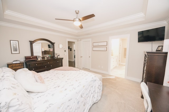 bedroom with ensuite bath, ceiling fan, light colored carpet, a tray ceiling, and ornamental molding