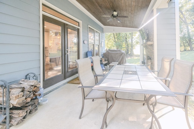 view of patio featuring an outdoor stone fireplace, ceiling fan, and grilling area