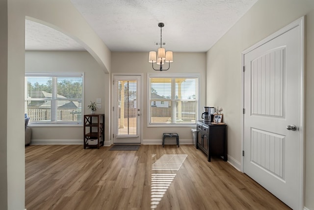 interior space with an inviting chandelier, light hardwood / wood-style flooring, and a textured ceiling