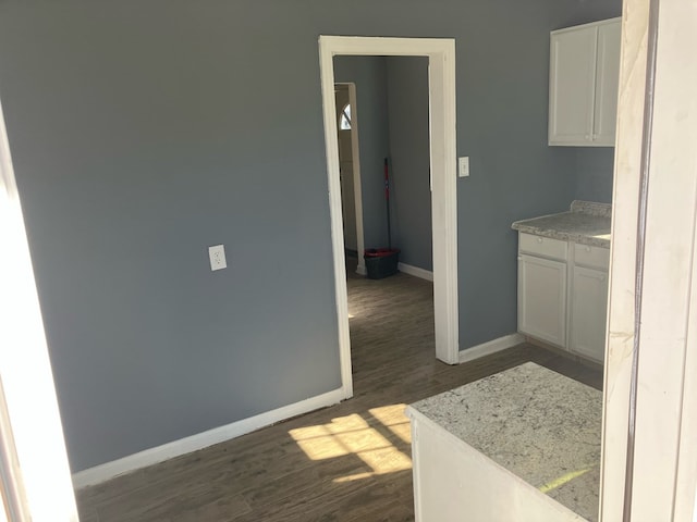 kitchen with white cabinets, dark hardwood / wood-style floors, and light stone counters